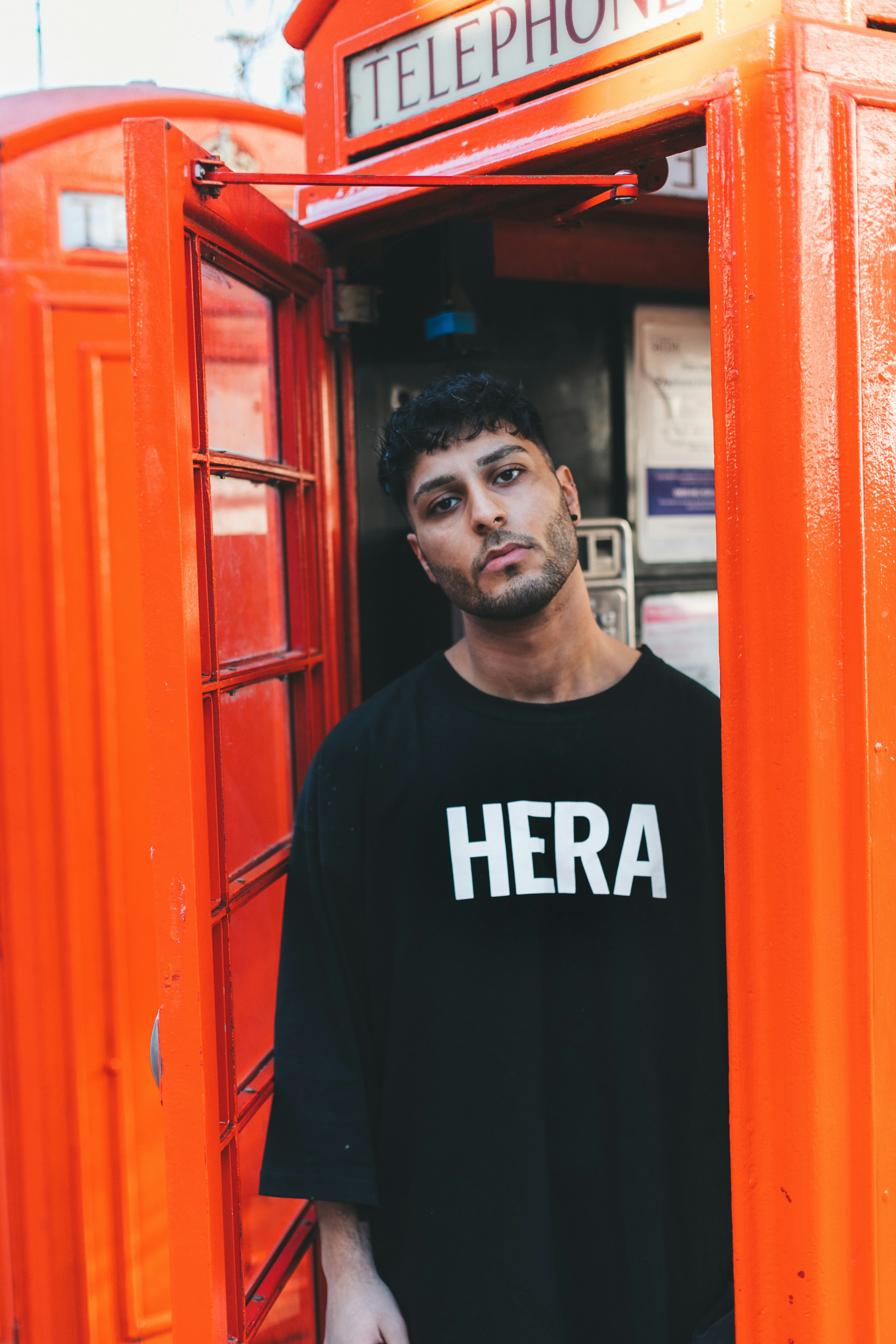 man standing inside telephone stall